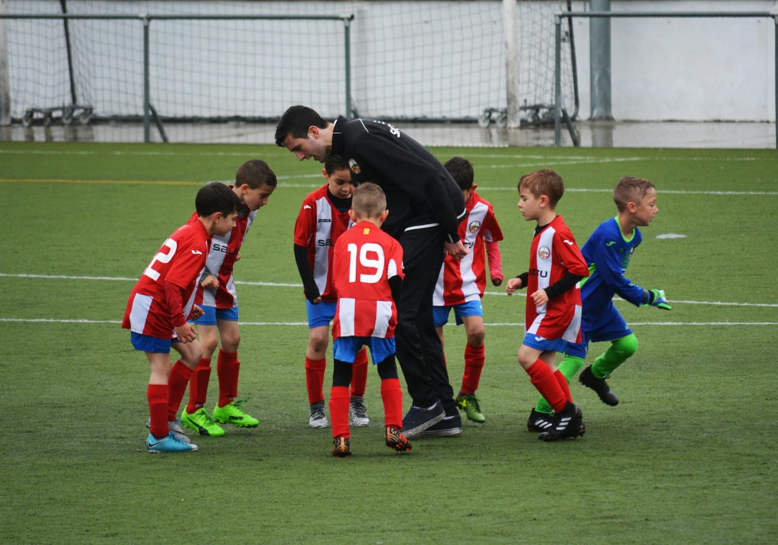 Peace Building: Coach talking with young footballers on the pitch at a Peace Cup-style tournament